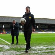 Referee Don Robertson walks off the soggy Dens Park pitch